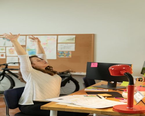 office worker stretching arms at modern desk